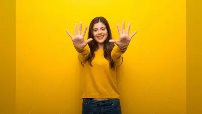 Teenager girl on vibrant yellow background counting ten with fingers